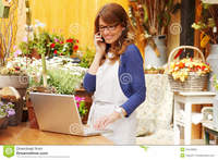 mature photos smiling mature woman florist small business flower shop owner using telephone laptop take orders store photos